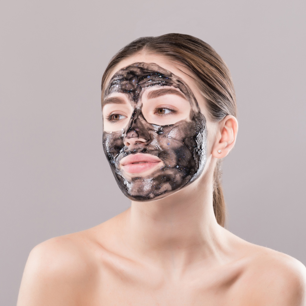 Молодая девушка с косметической черной маской на лице