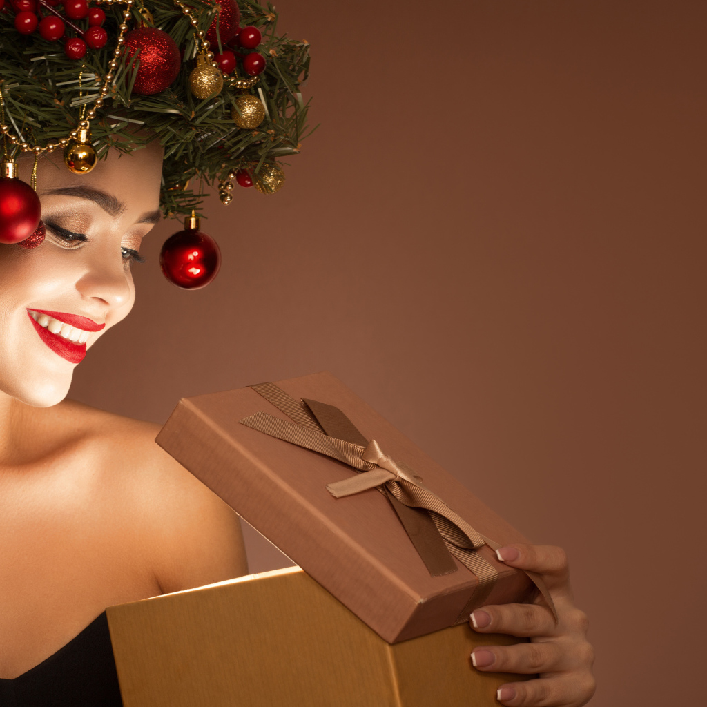 Красивая девушка с рождественским венком на голове с подарком