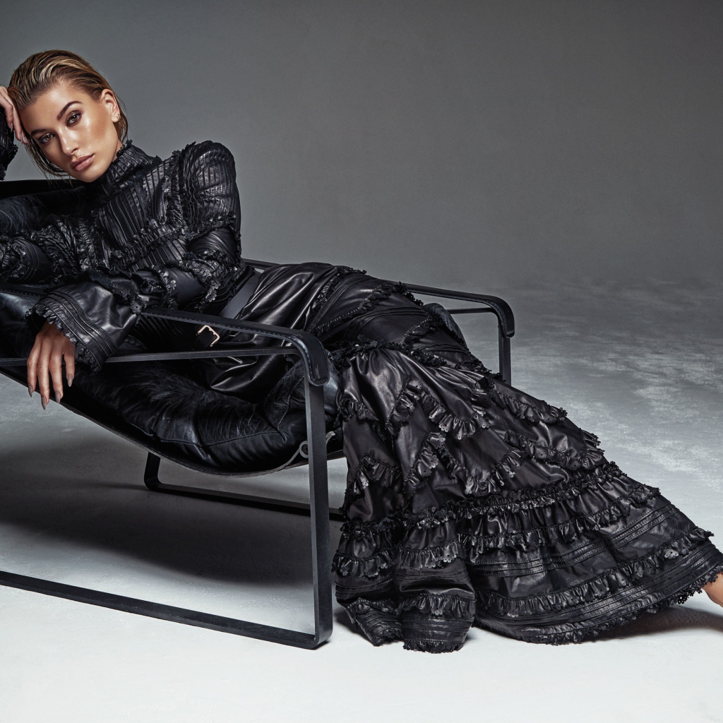 Красивая модель Хейли Болдуин в длинном платье лежит в кресле
