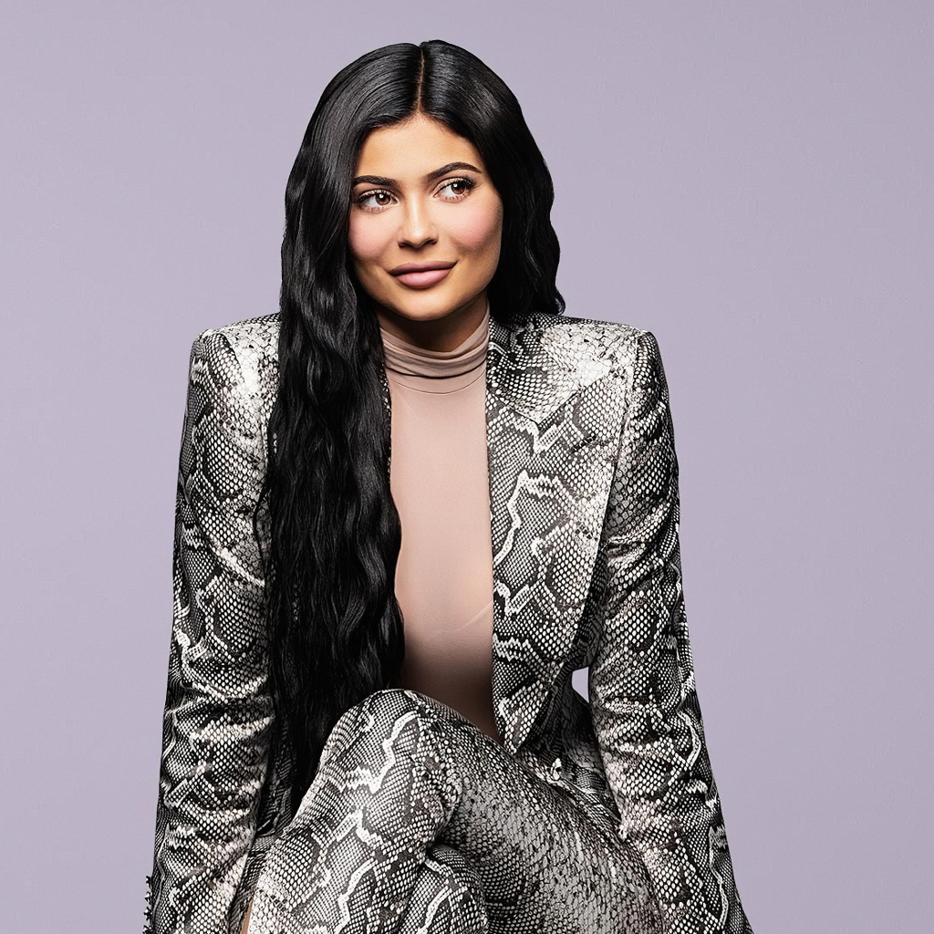Длинноволосая модель Кайли Дженнер в костюме на сером фоне