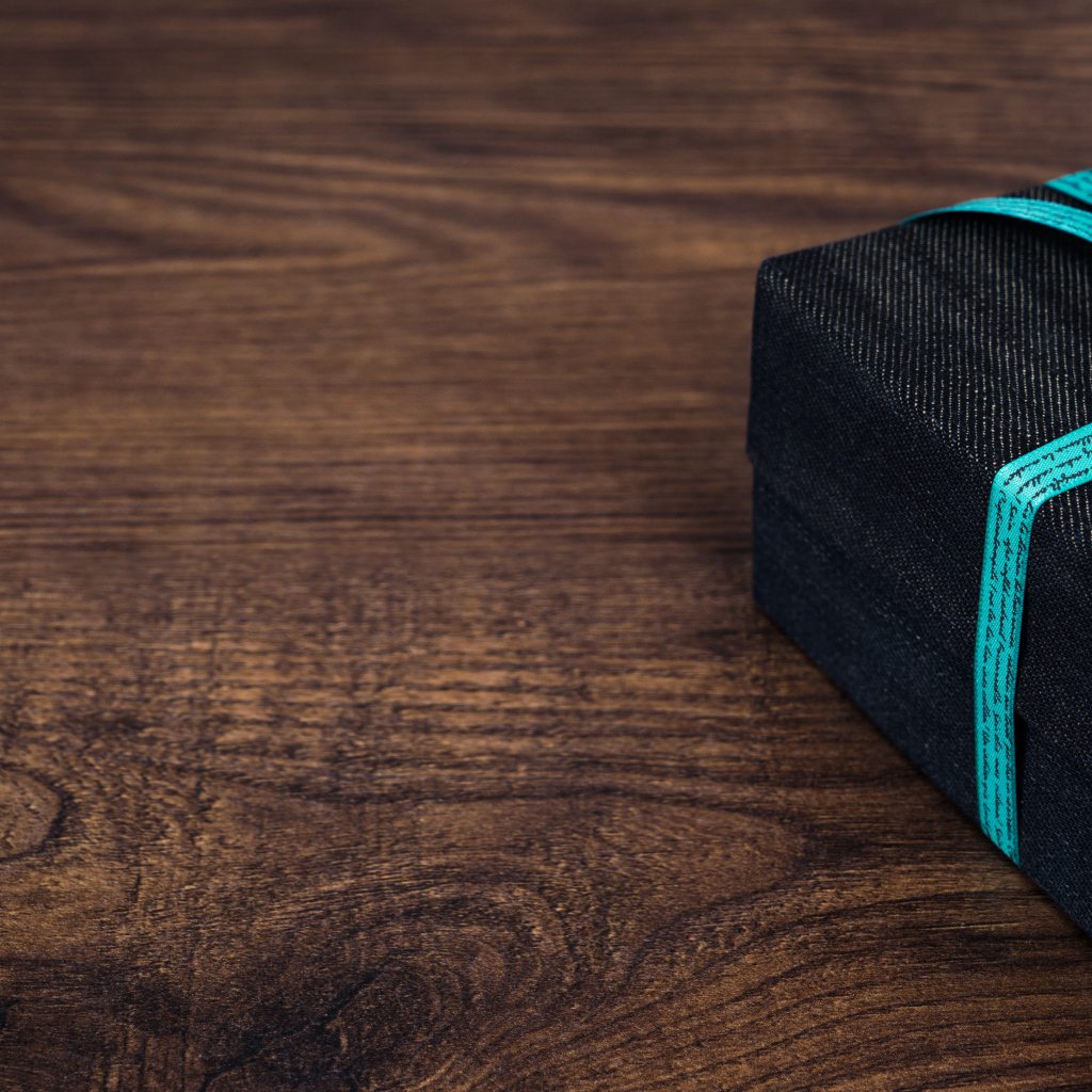 Подарок с синим бантом на деревянном столе 