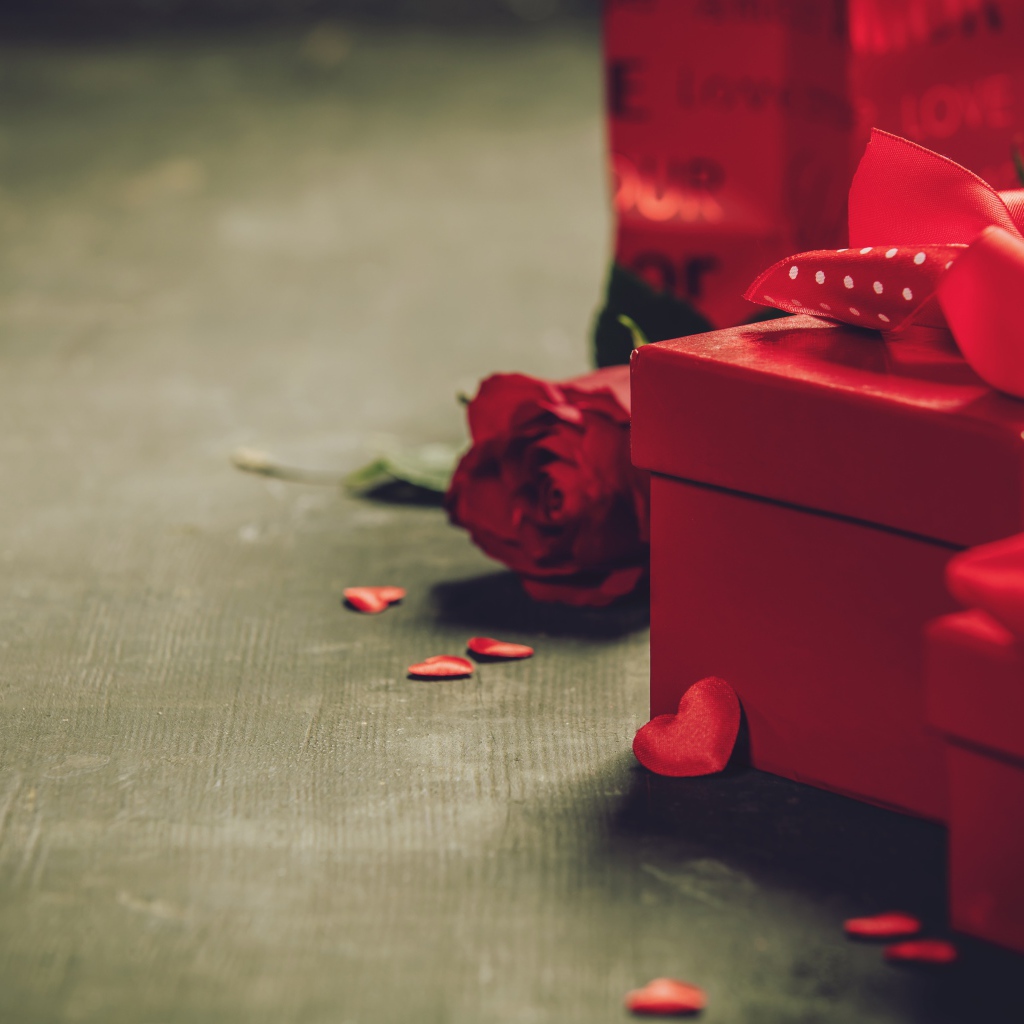 Красные коробки с подарками на столе с розой 