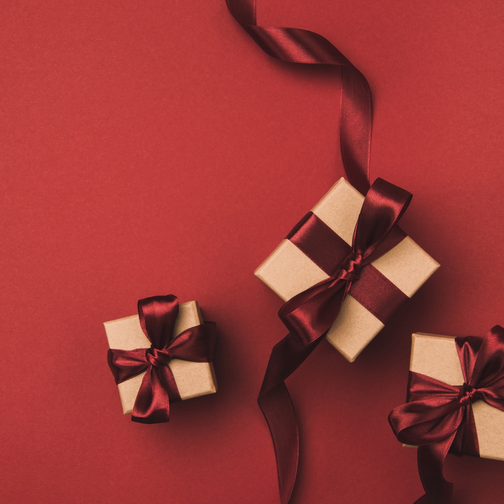 Three gift boxes with bows on a red background.