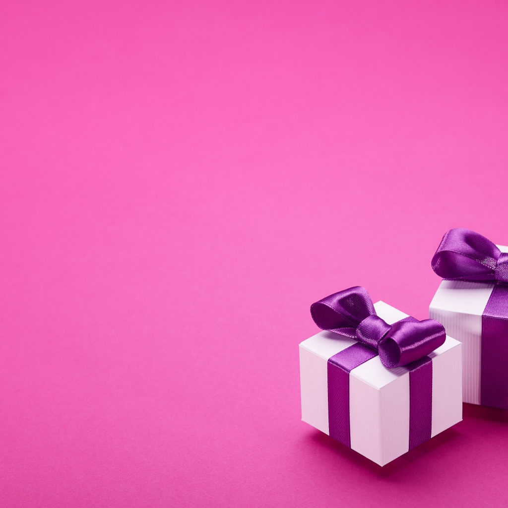 Два подарка с бантами на розовом фоне 