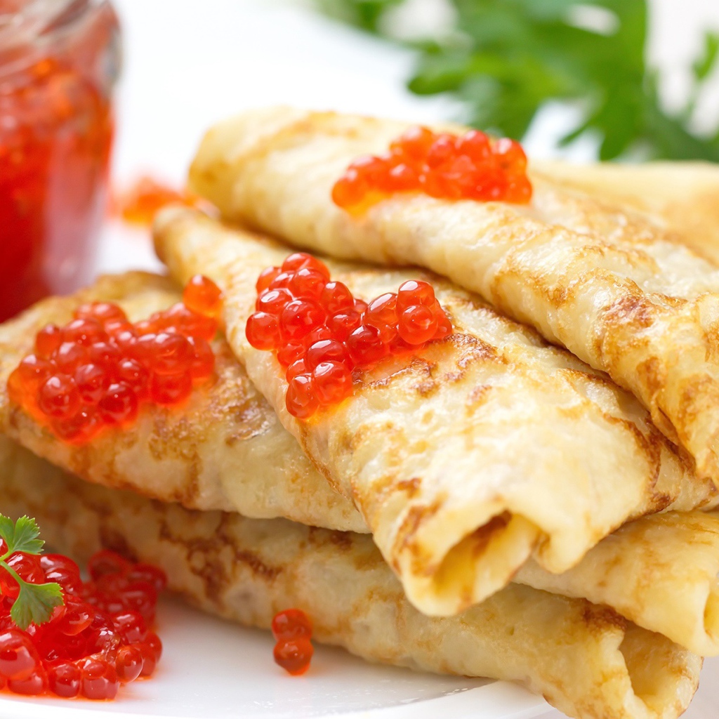 Аппетитные тонкие блины с красной икрой на тарелке с петрушкой угощение на Масленицу