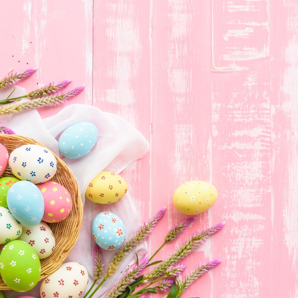 Корзина с крашеными яйцами на розовом фоне