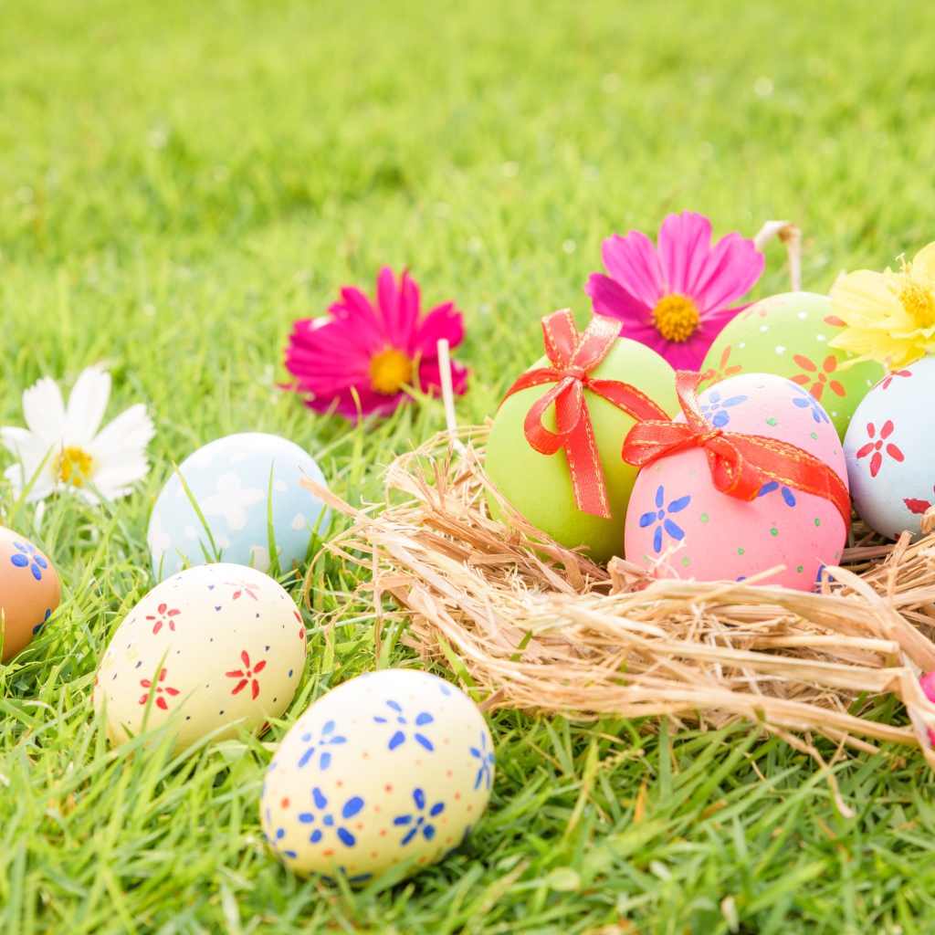 Разноцветные яйца в гнезде на зеленой траве на Пасху
