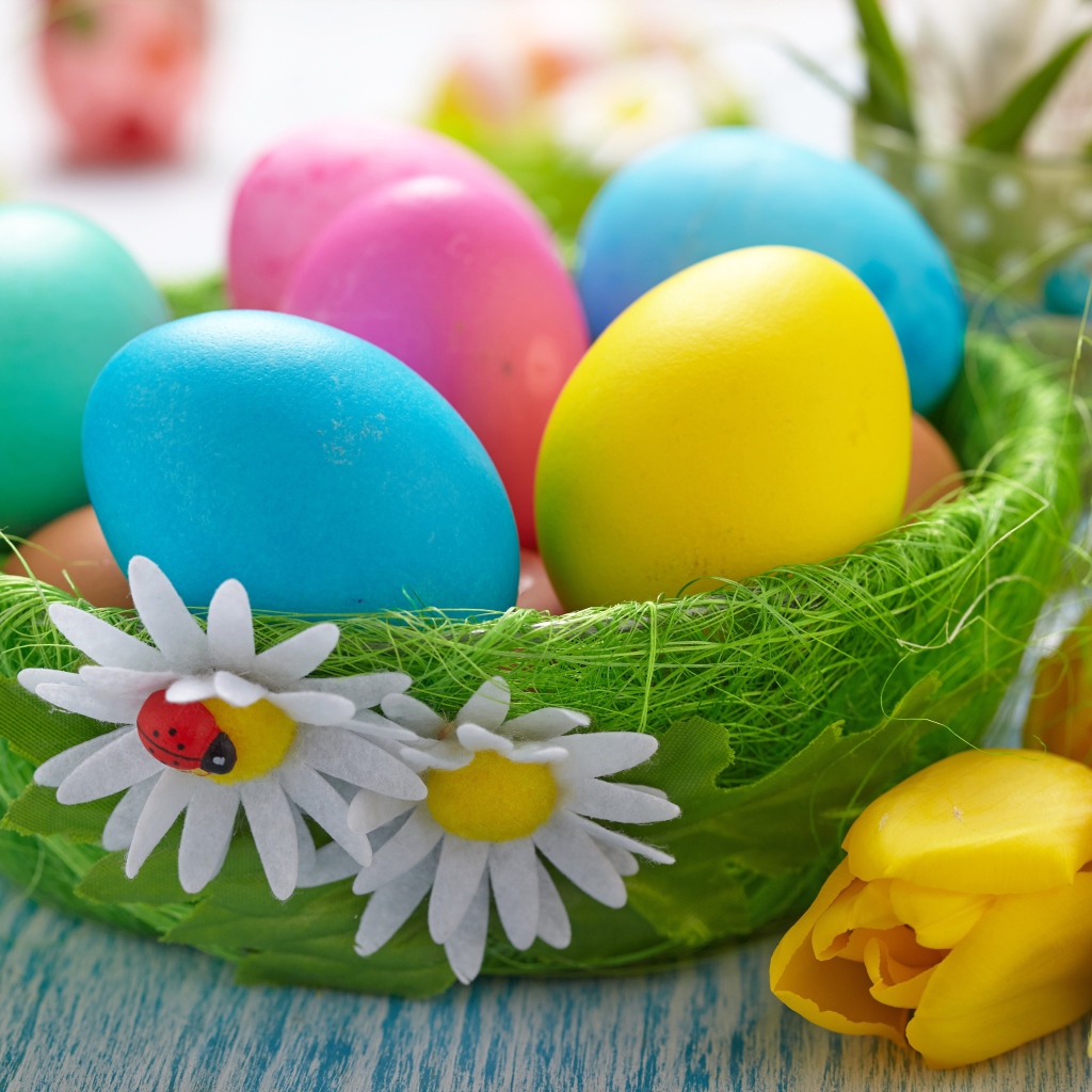 Разноцветные яйца на столе с тюльпанами на Пасху