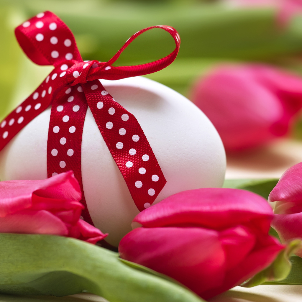 Яйцо с бантом на столе с тюльпанами на праздник Пасха