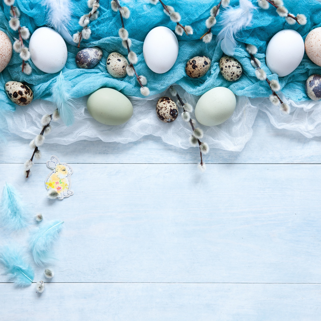 Яйца на ткани с ветками вербы на столе