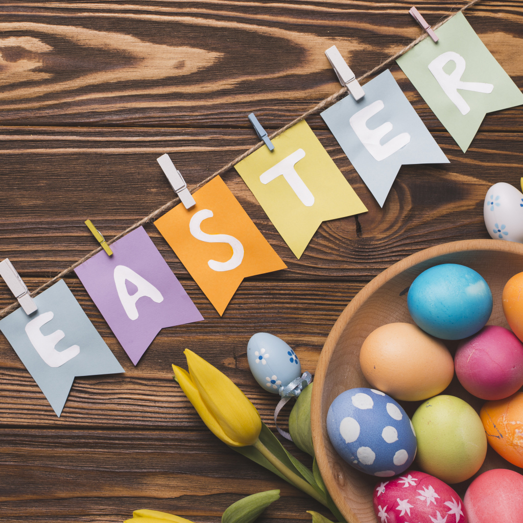 Надпись Пасха на столе с крашеными яйцами и тюльпанами