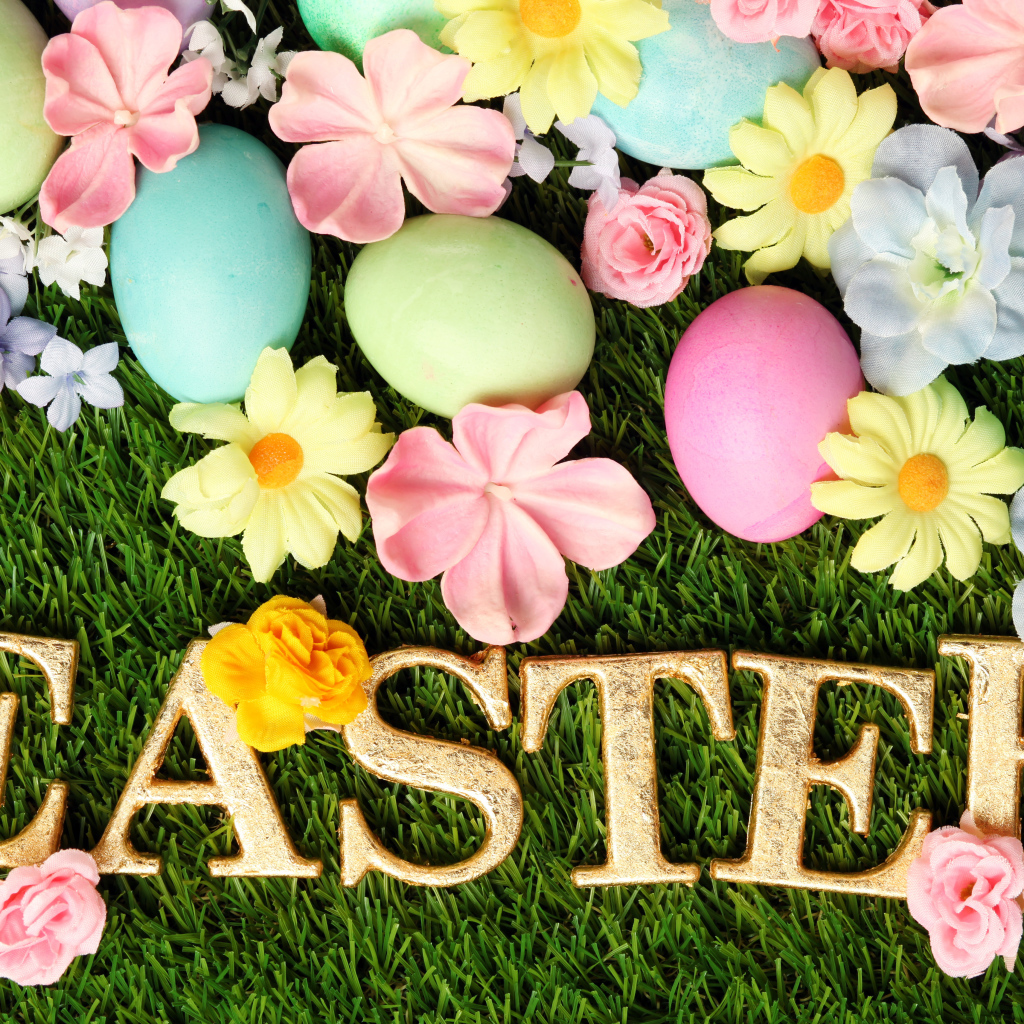 Надпись на траве с разноцветными яйцами и цветами на Пасху
