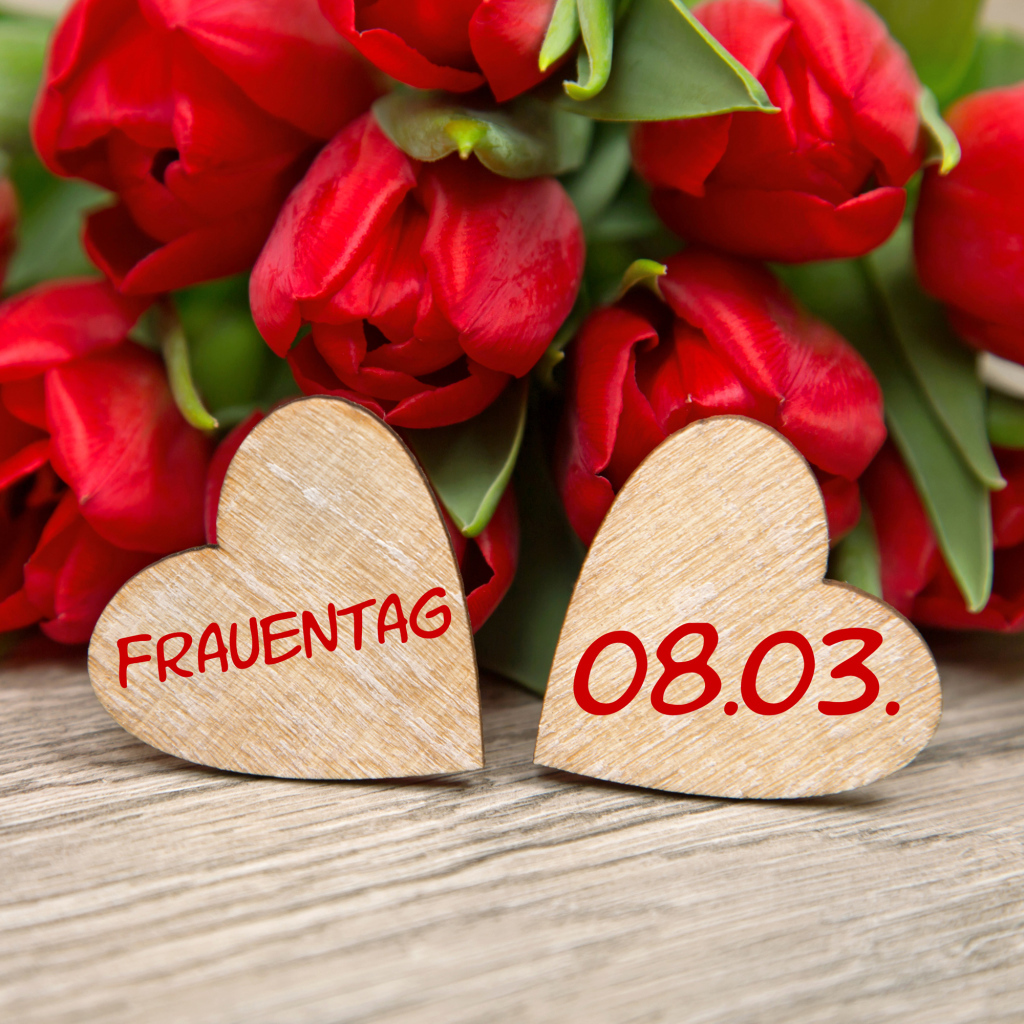 Два сердечка на столе с букетом красных тюльпанов на 8 марта 