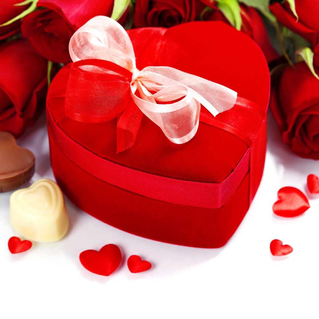 Красная коробка в форме сердца на столе с розами и конфетами для любимой