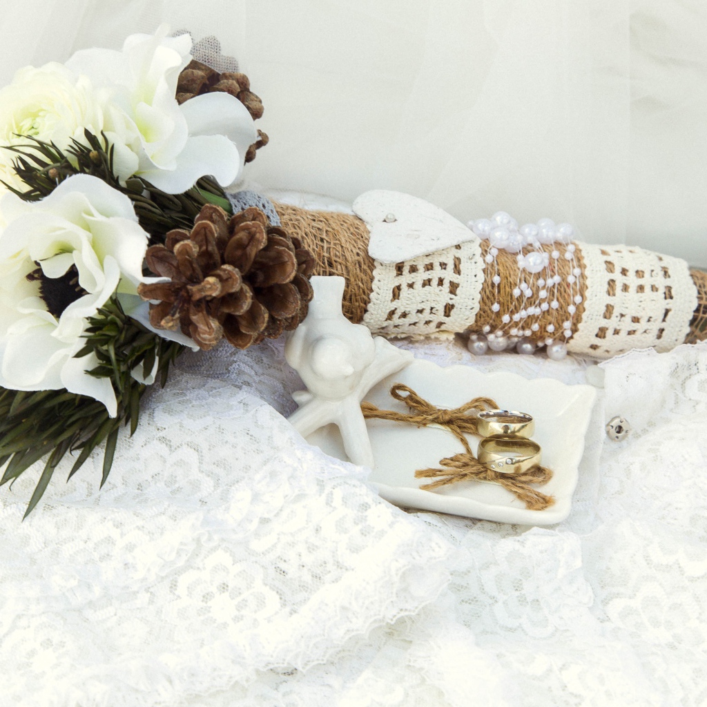 Букет невесты из цветом анемоны лежит на платье с обручальными кольцами