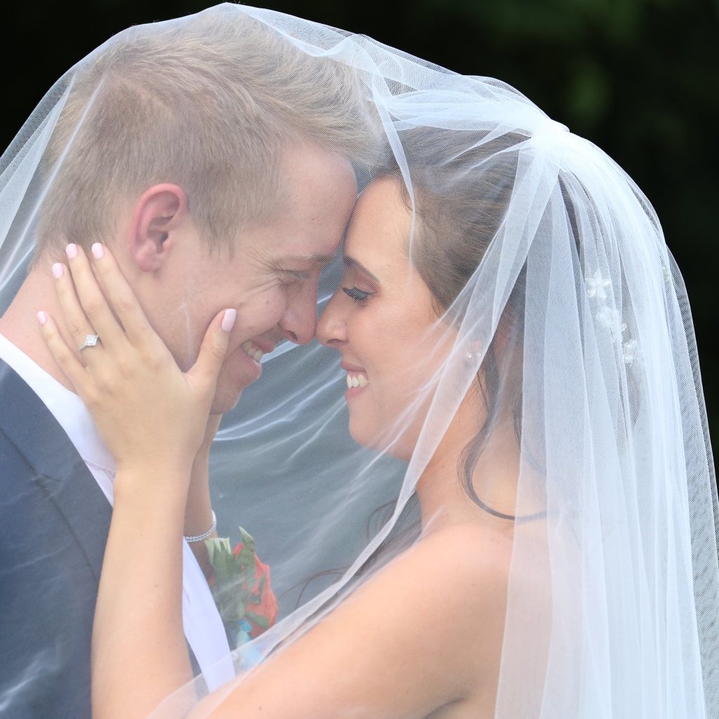 Жених и невеста стоят под белой фатой