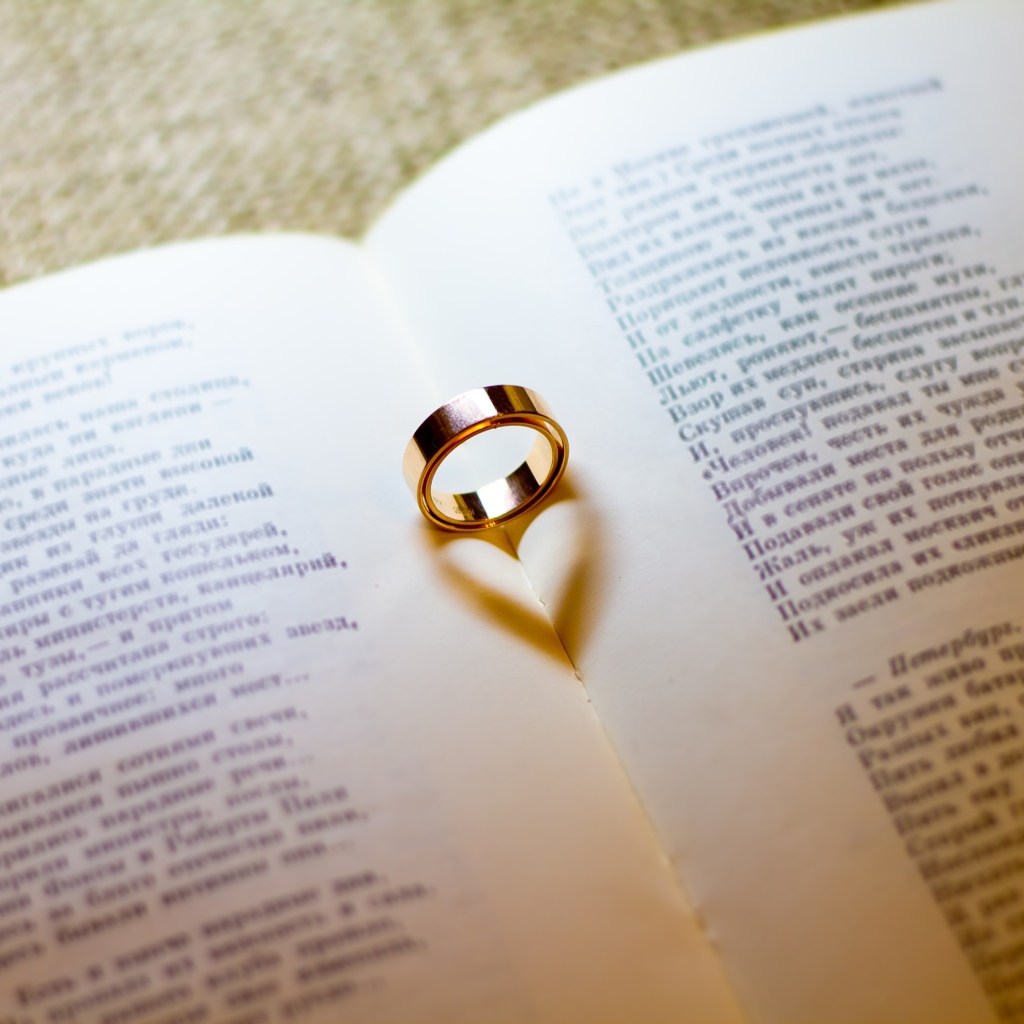 Золотое обручальное кольцо лежит на открытой книге