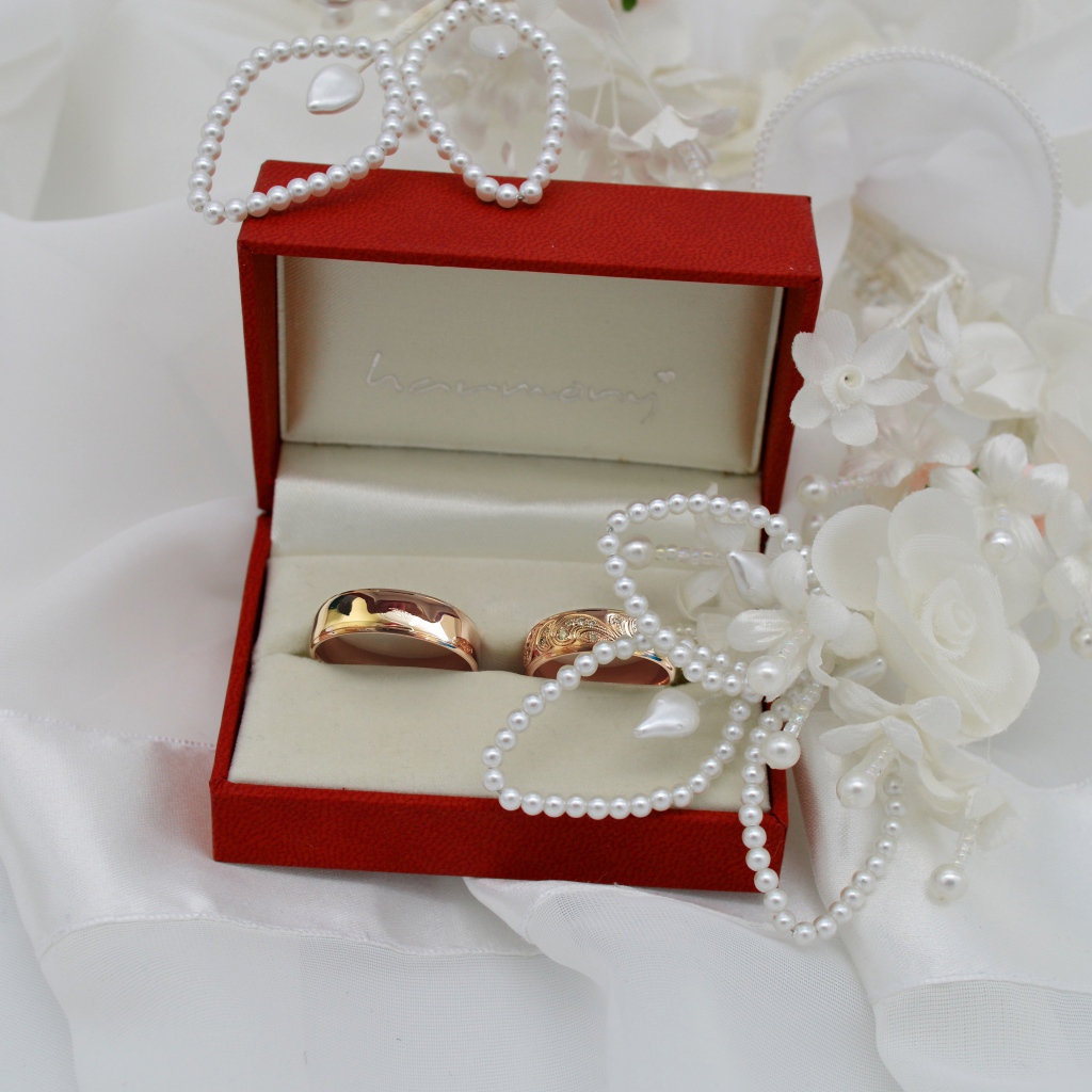 Золотые обручальные кольца в красной коробочке с украшениями