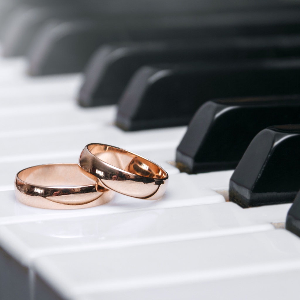 Два золотых обручальных кольца на клавишах рояля 