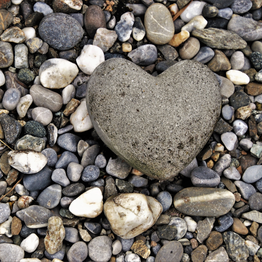 Большой камень в форме сердца лежит на морской гальке