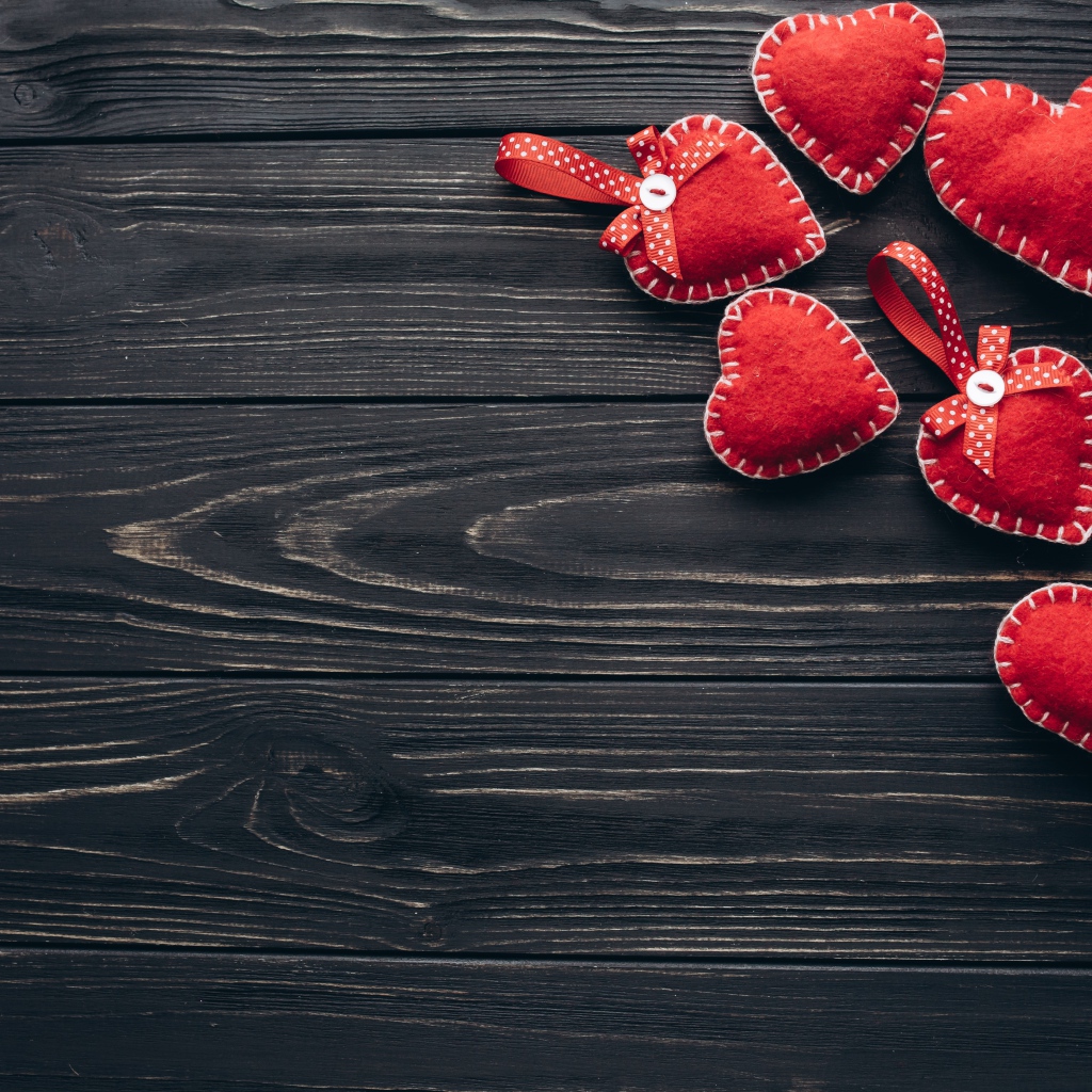 Много красных сердечек из фетра на деревянном столе
