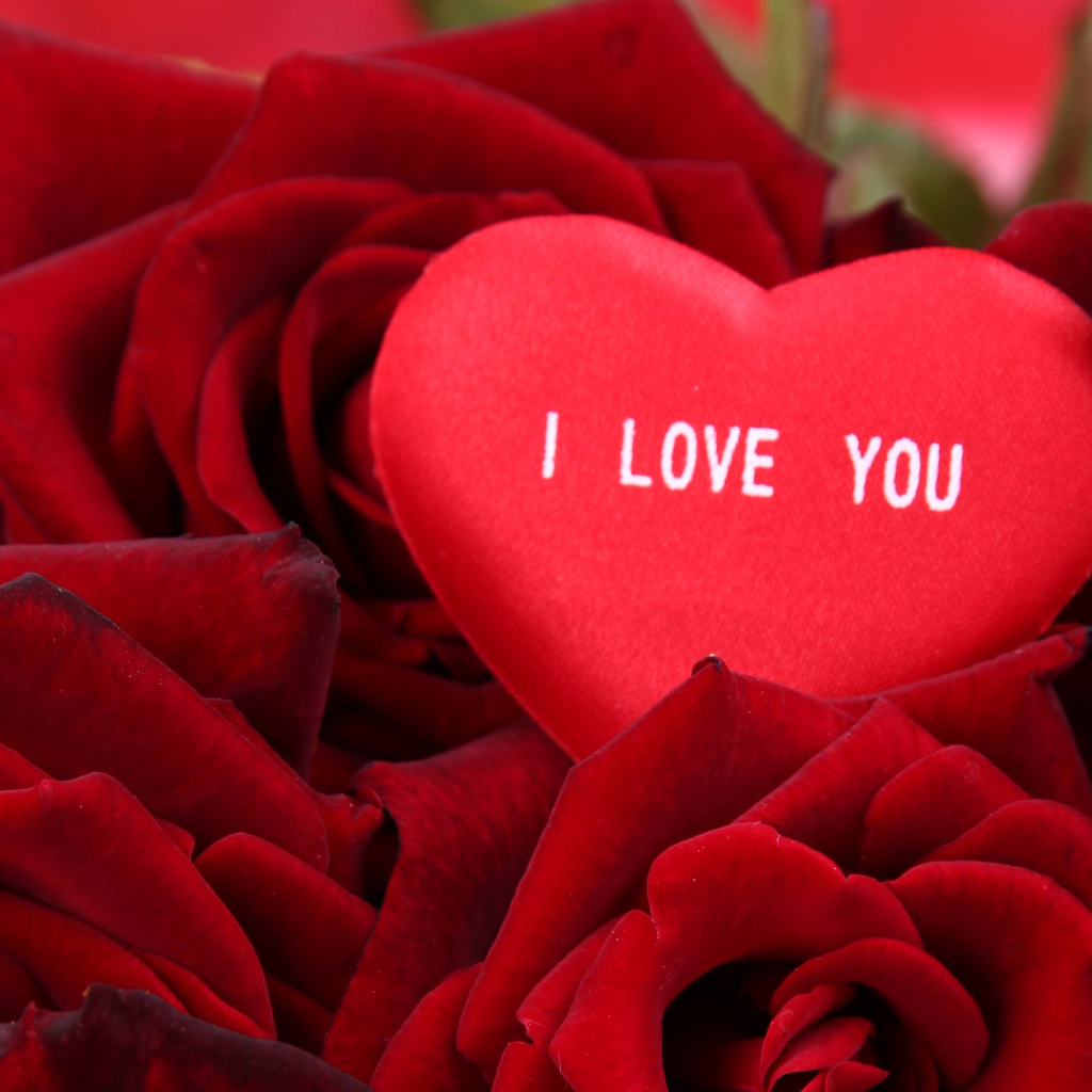 Маленькое сердце лежит на букете красных роз 