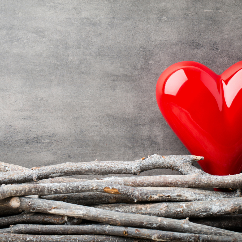 Большое красное сердце на сером фоне с деревянными прутьями