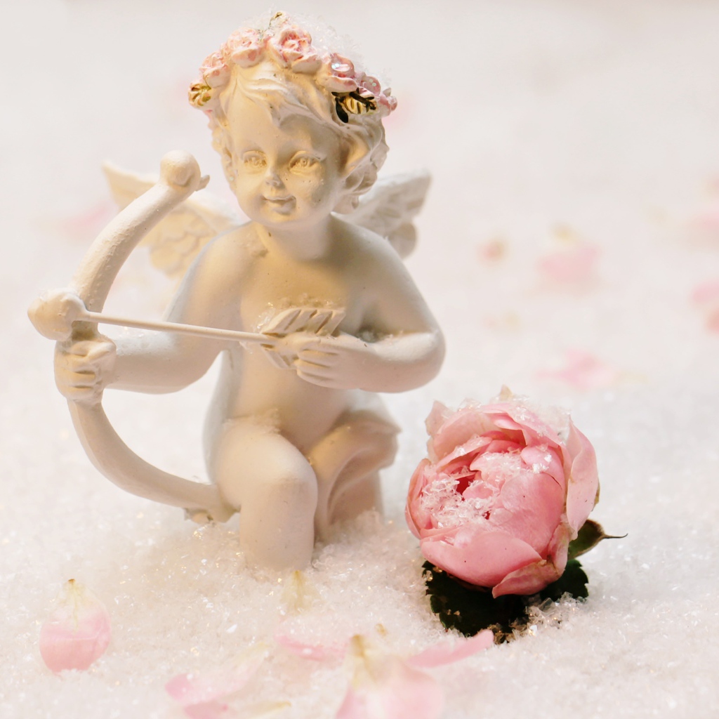 Cupid figurine with a rose in the snow