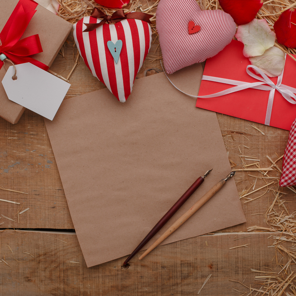 Сердечки из ткани на столе с бумагой и подарками 