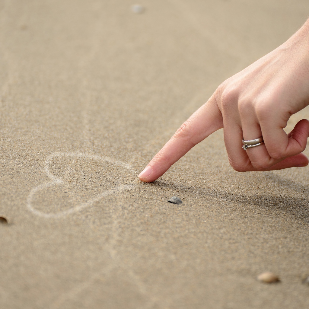 Girl draws a heart on the sand