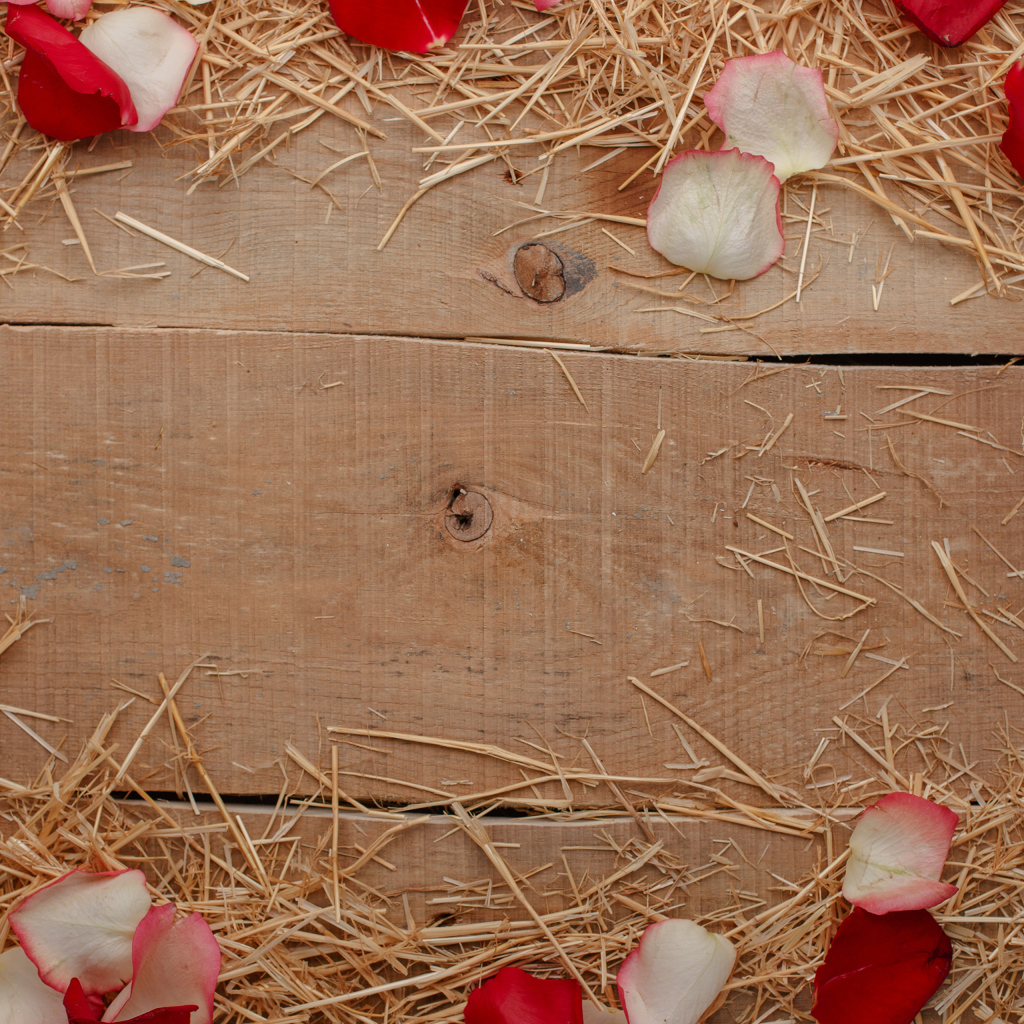 Сено и лепестки роз на деревянном столе 