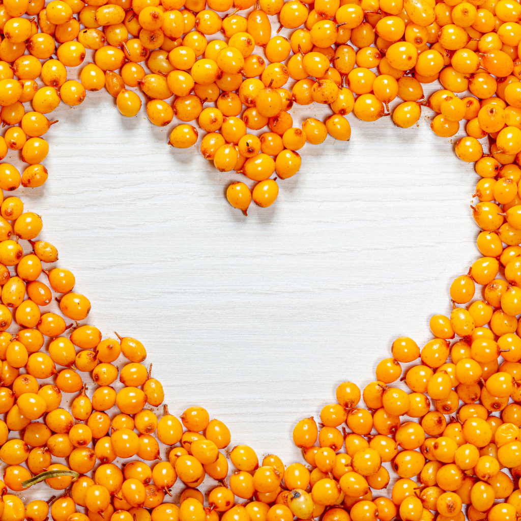 Сердце из ягод облепихи на столе 