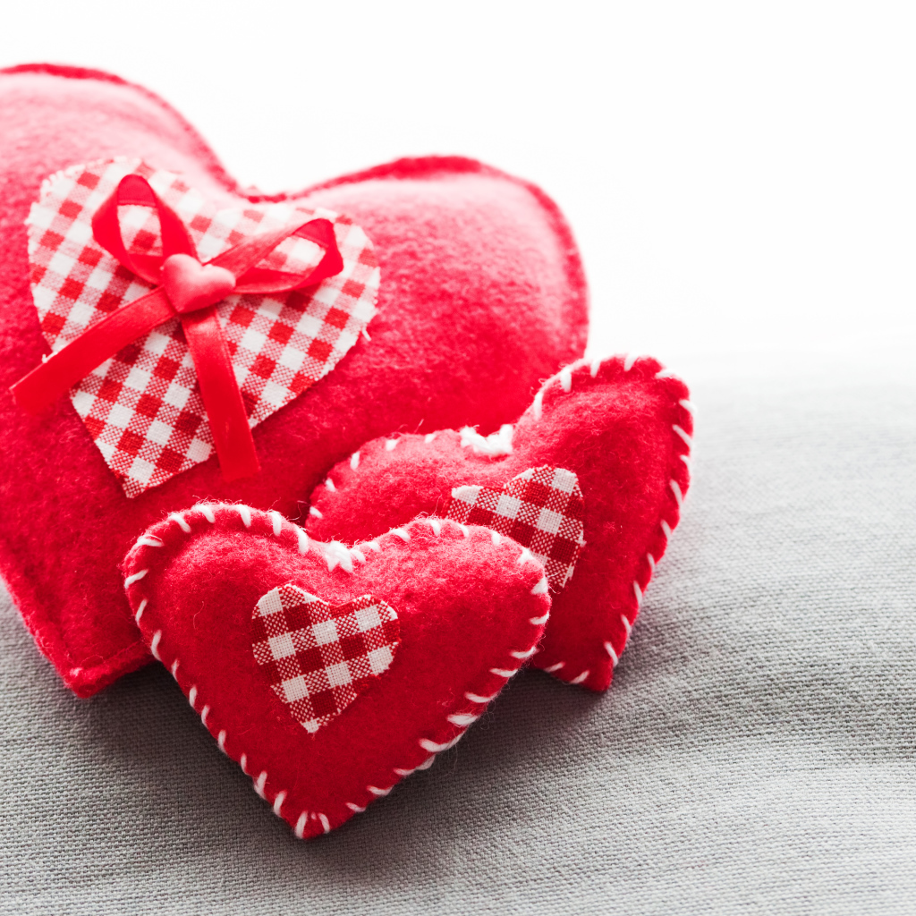 Сердечки из ткани лежат на серой поверхности 