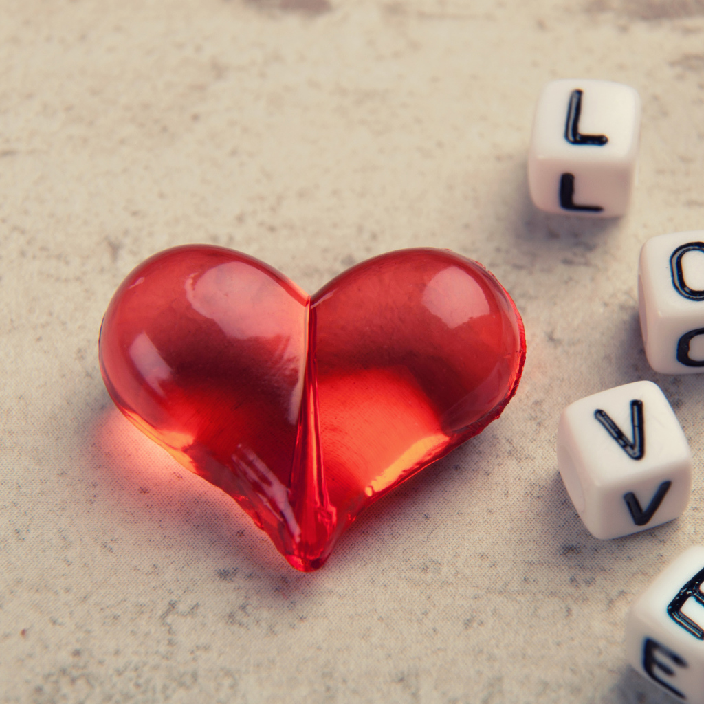 Красное стеклянное сердце на столе с кубиками