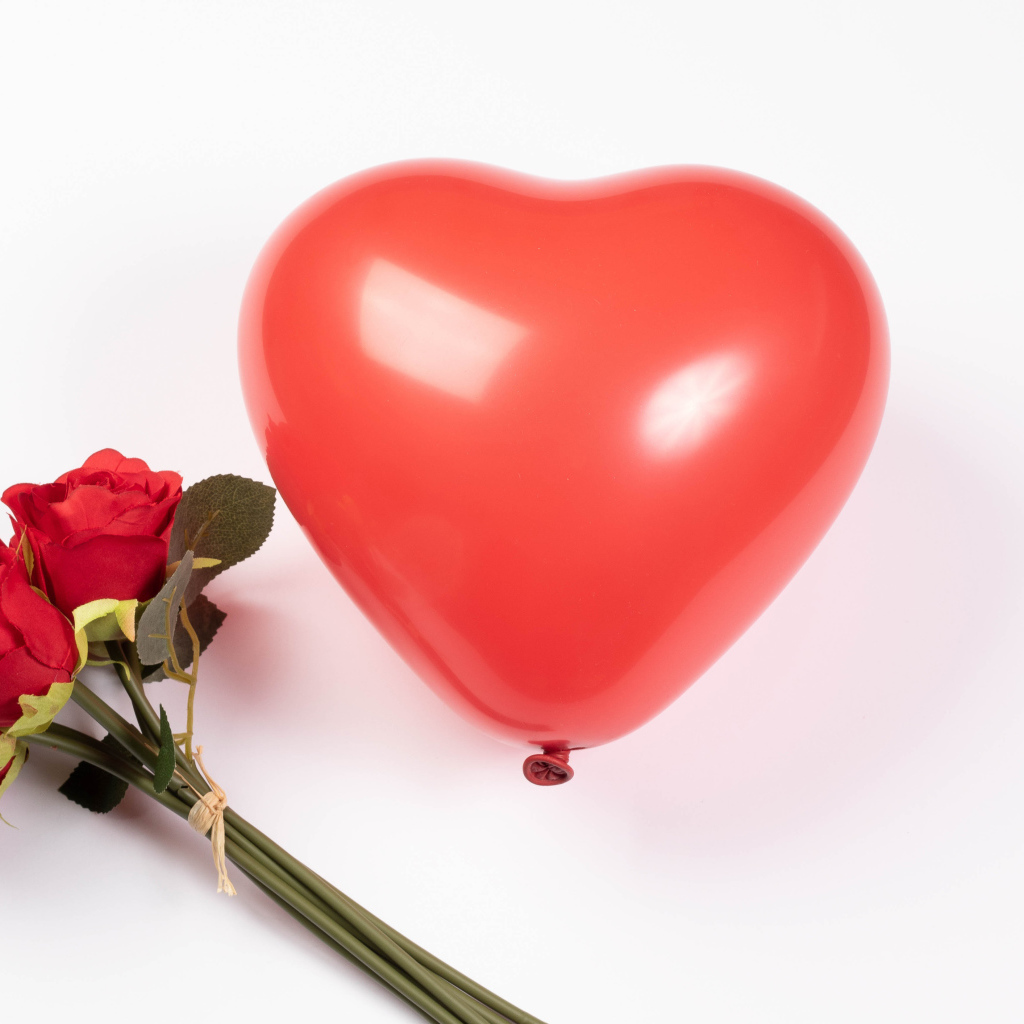 Красный шарик в форме сердца с букетом роз на белом фоне