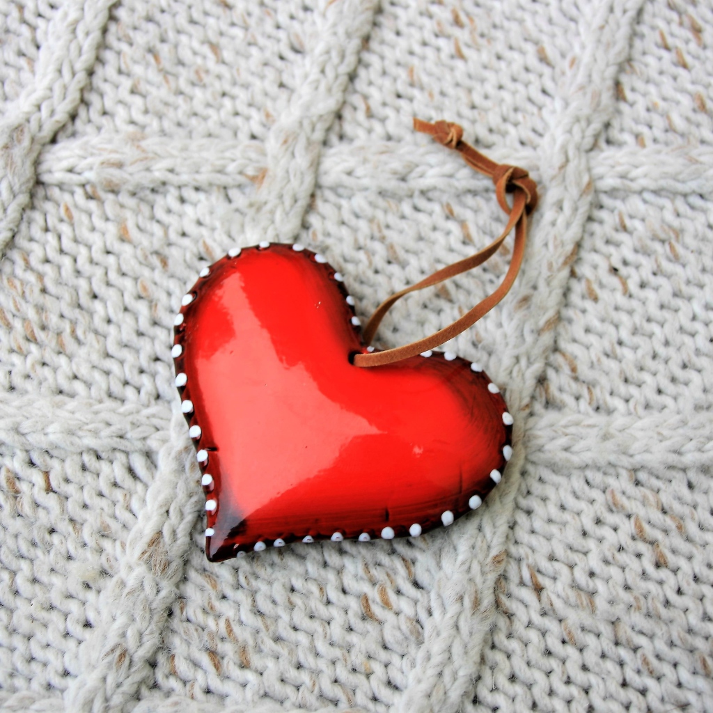 Красное сердце лежит на вязаном свитере 