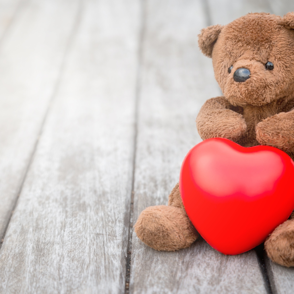 Медвежонок Тедди с красным сердцем сидит на столе