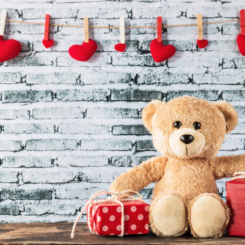 Медвежонок Тедди с подарками на фоне стены с сердечками