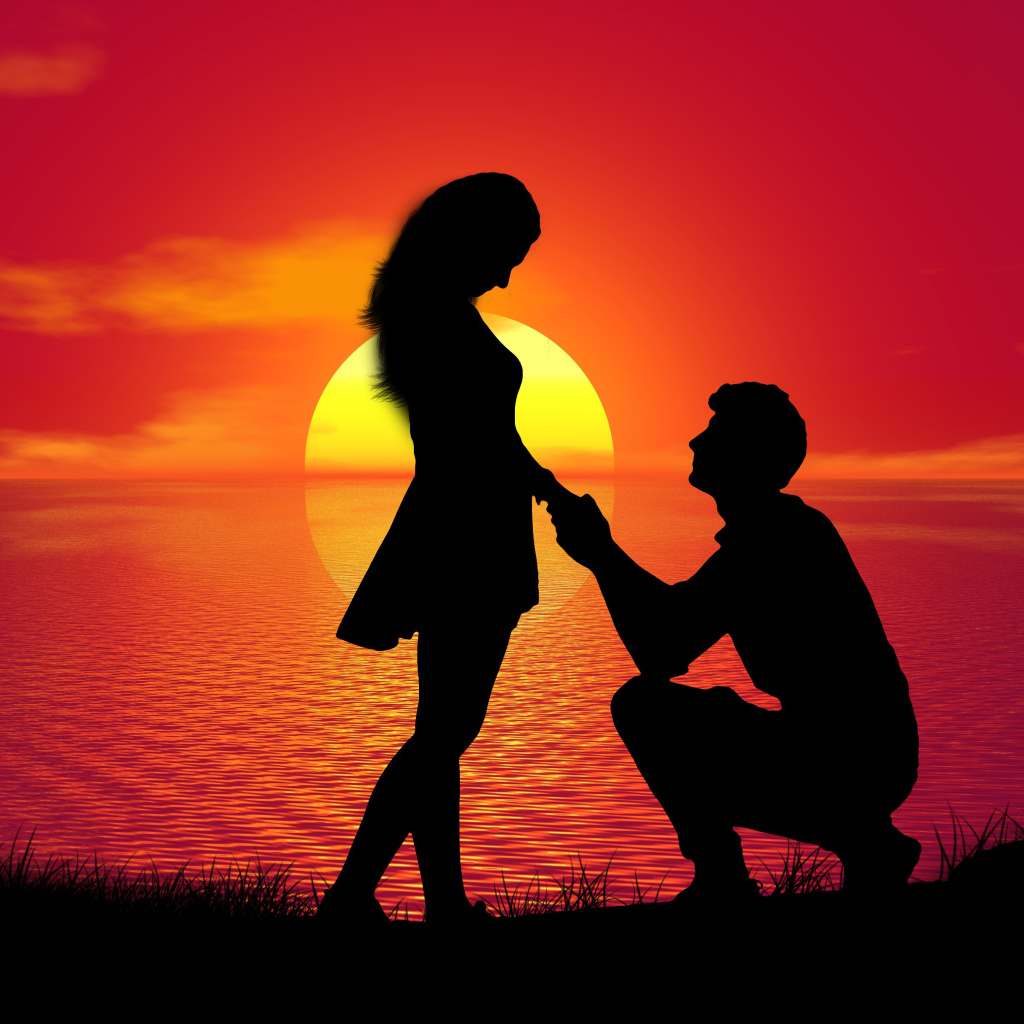 Парень делает девушке предложение на фоне заката у моря