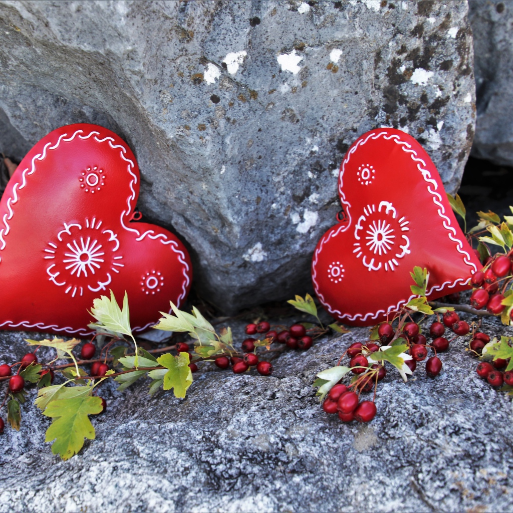 Два сердца лежат у камня с красными ягодами