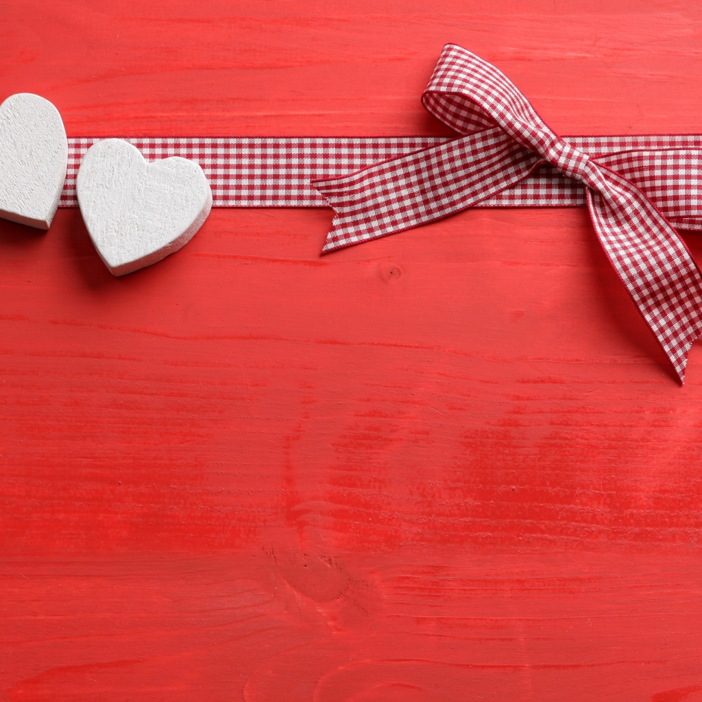 Два сердечка с бантом на красном фоне