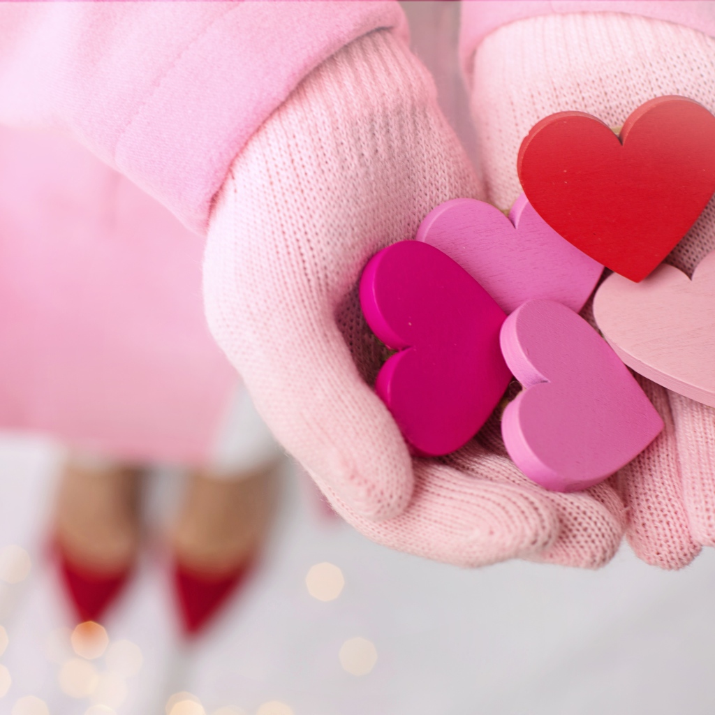 Деревянные сердечки в руках девушки в розовых перчатках 