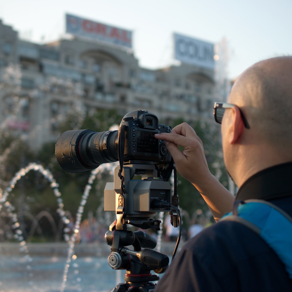 Мужчина снимает на камеру фонтан в парке