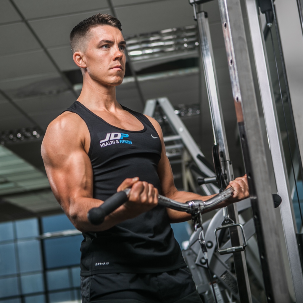 Накаченный мужчина занимается на тренажере в спортзале