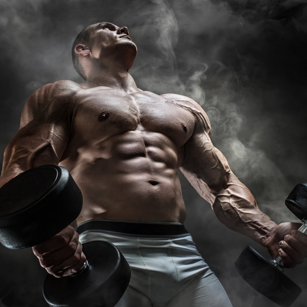 Мужчина бодибилдер с тяжелыми гантелями в руках
