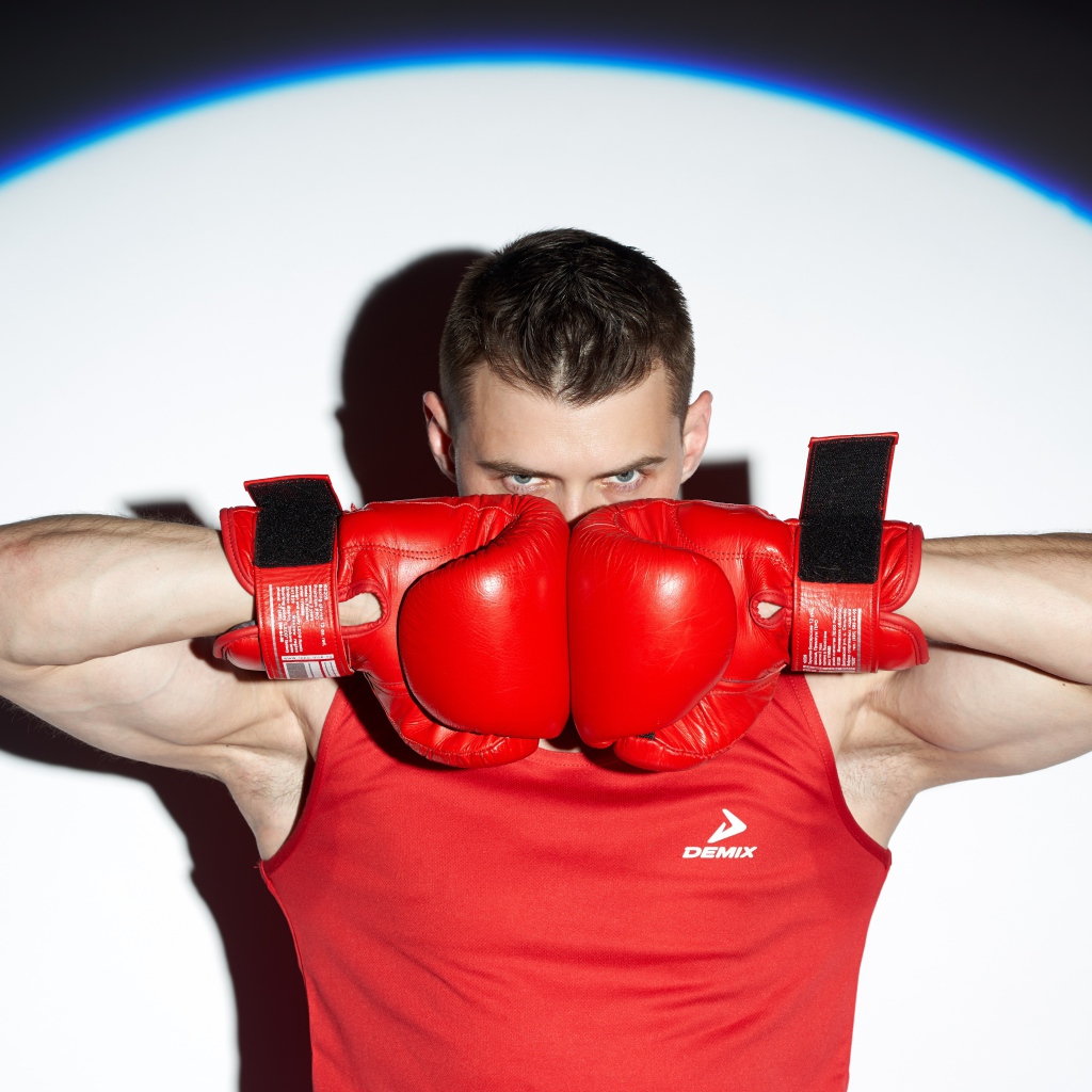 Мужчина боксер с красных перчатках в свете прожектора 