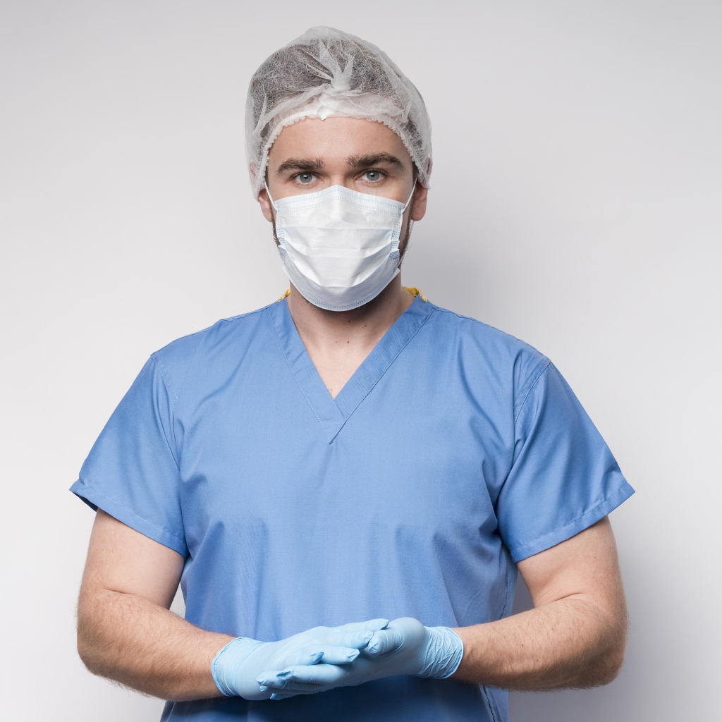 Мужчина врач в маске и перчатках на сером фоне