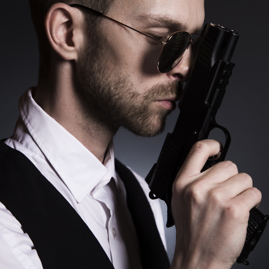 Man in glasses with a gun in his hand.