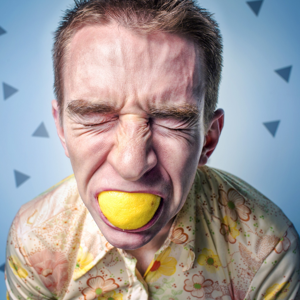Мужчина с закрытыми глазами ест лимон 