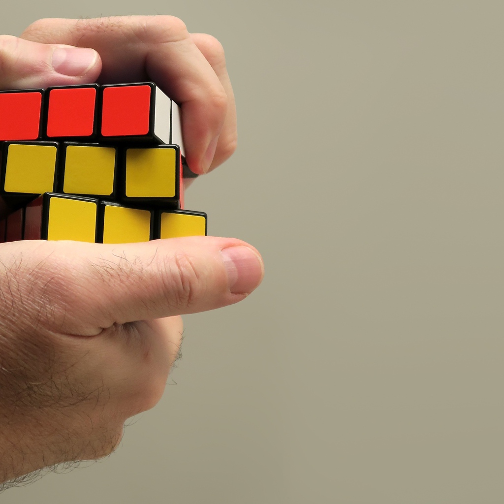 Rubik's cube in the hands of a man on a gray background